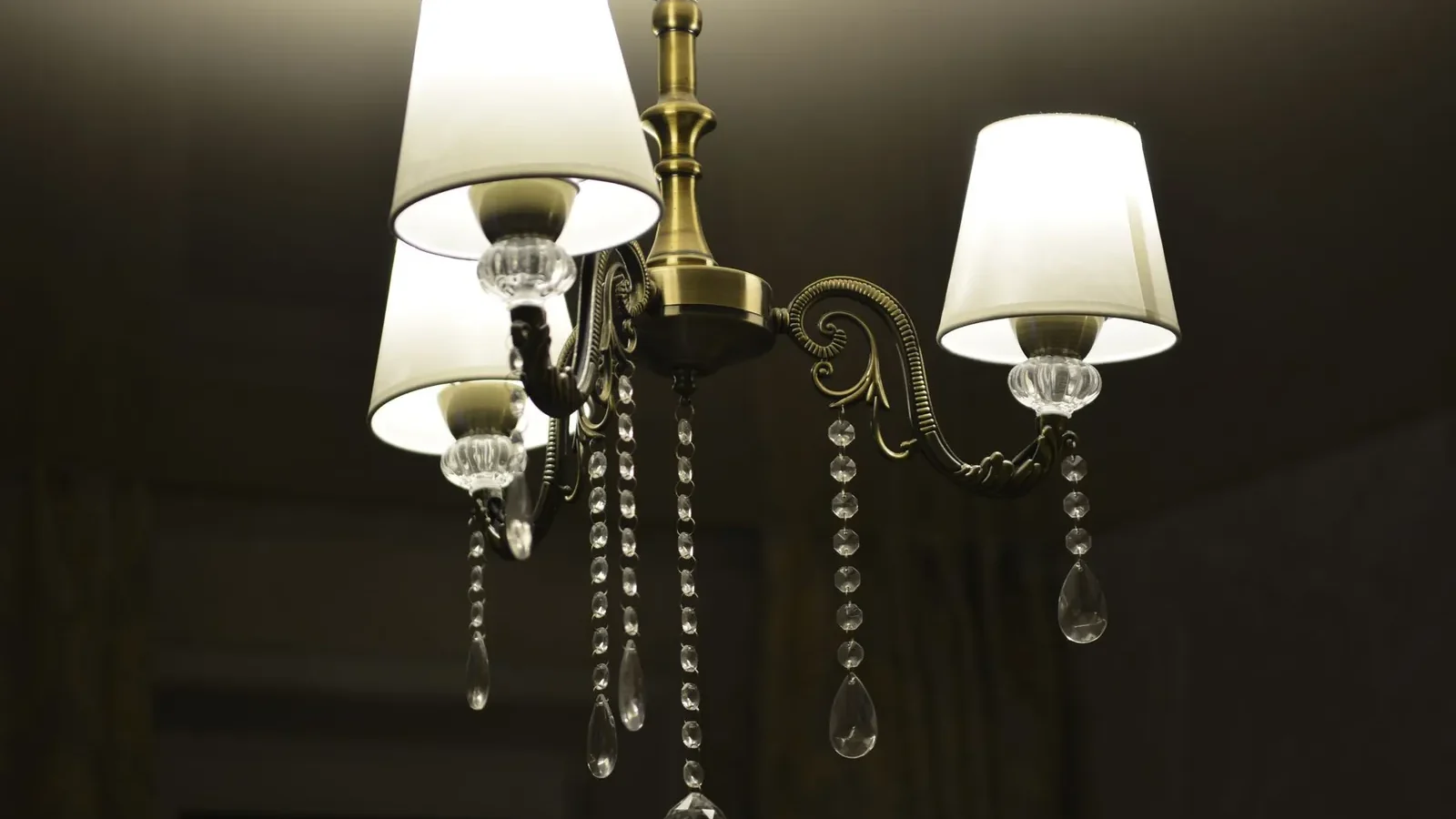 Layered living room lighting showing a ceiling flush-mount for ambient light, an arc floor lamp beside an armchair for task light, and a wall sconce providing accent light