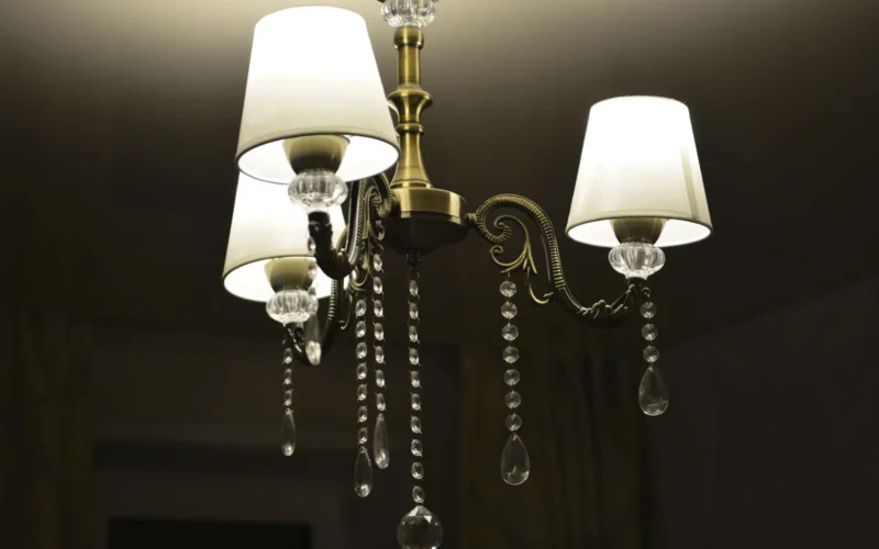 Layered living room lighting showing a ceiling flush-mount for ambient light, an arc floor lamp beside an armchair for task light, and a wall sconce providing accent light