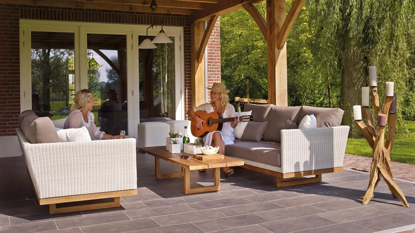 Teak outdoor dining set with honey-brown finish on a stone patio