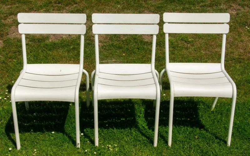 Outdoor dining chairs in teak, aluminum, and wicker styles arranged around a patio table