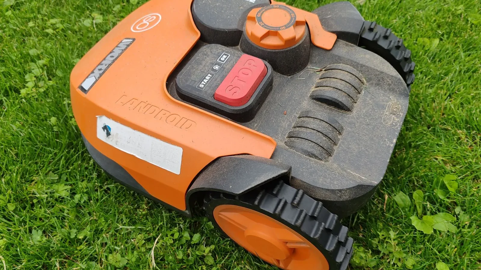 Compact robot lawn mower returning to its docking station on a tidy quarter-acre residential lawn