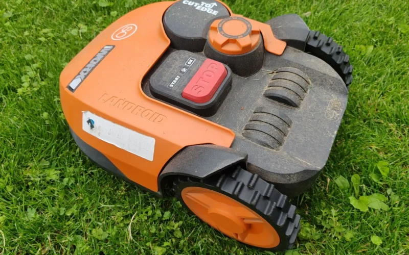 Compact robot lawn mower returning to its docking station on a tidy quarter-acre residential lawn