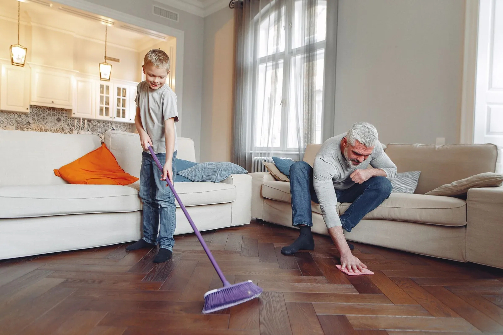 A family of four dividing weekend cleaning tasks with a visible chore chart on the kitchen wall