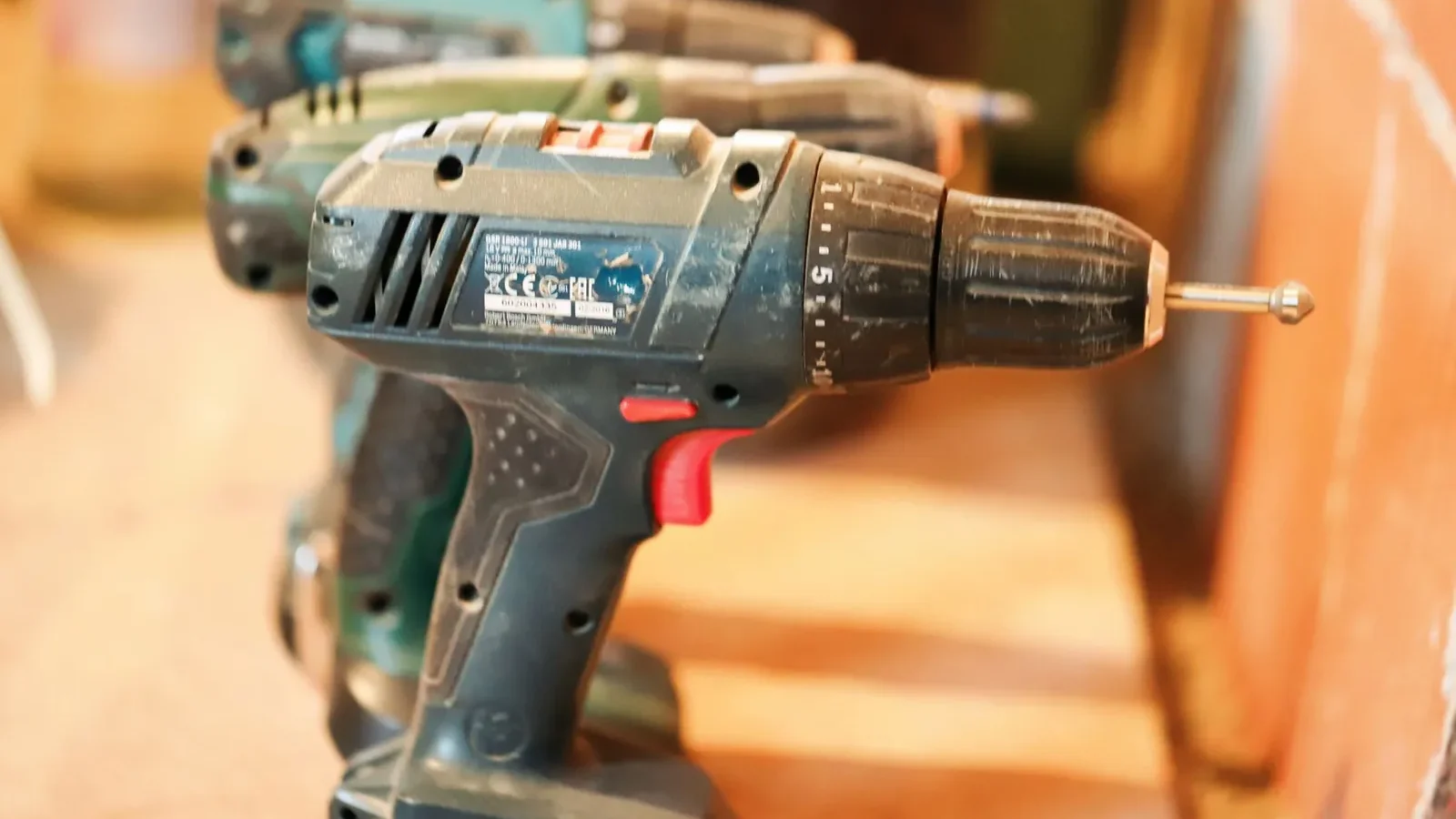 Cordless drill with 4.0 Ah battery pack beside a corded drill with coiled power cord on a workbench