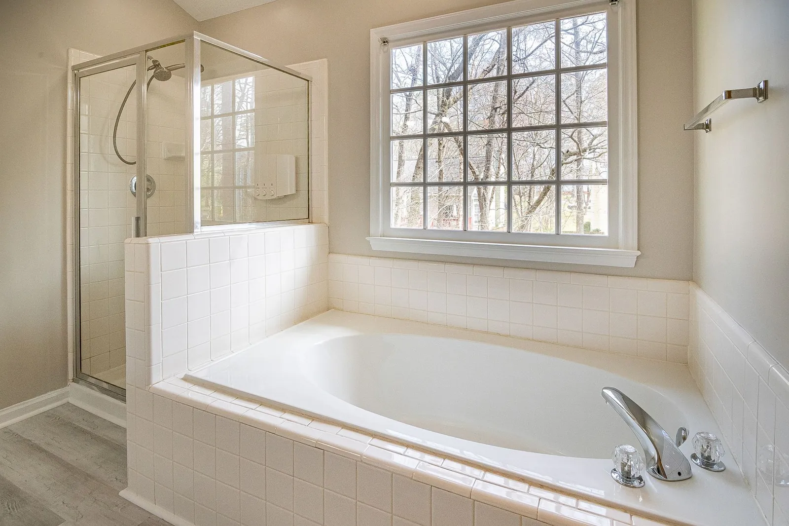 Caulk gun held at 45-degree angle applying a silicone bead along a bathtub-to-tile joint