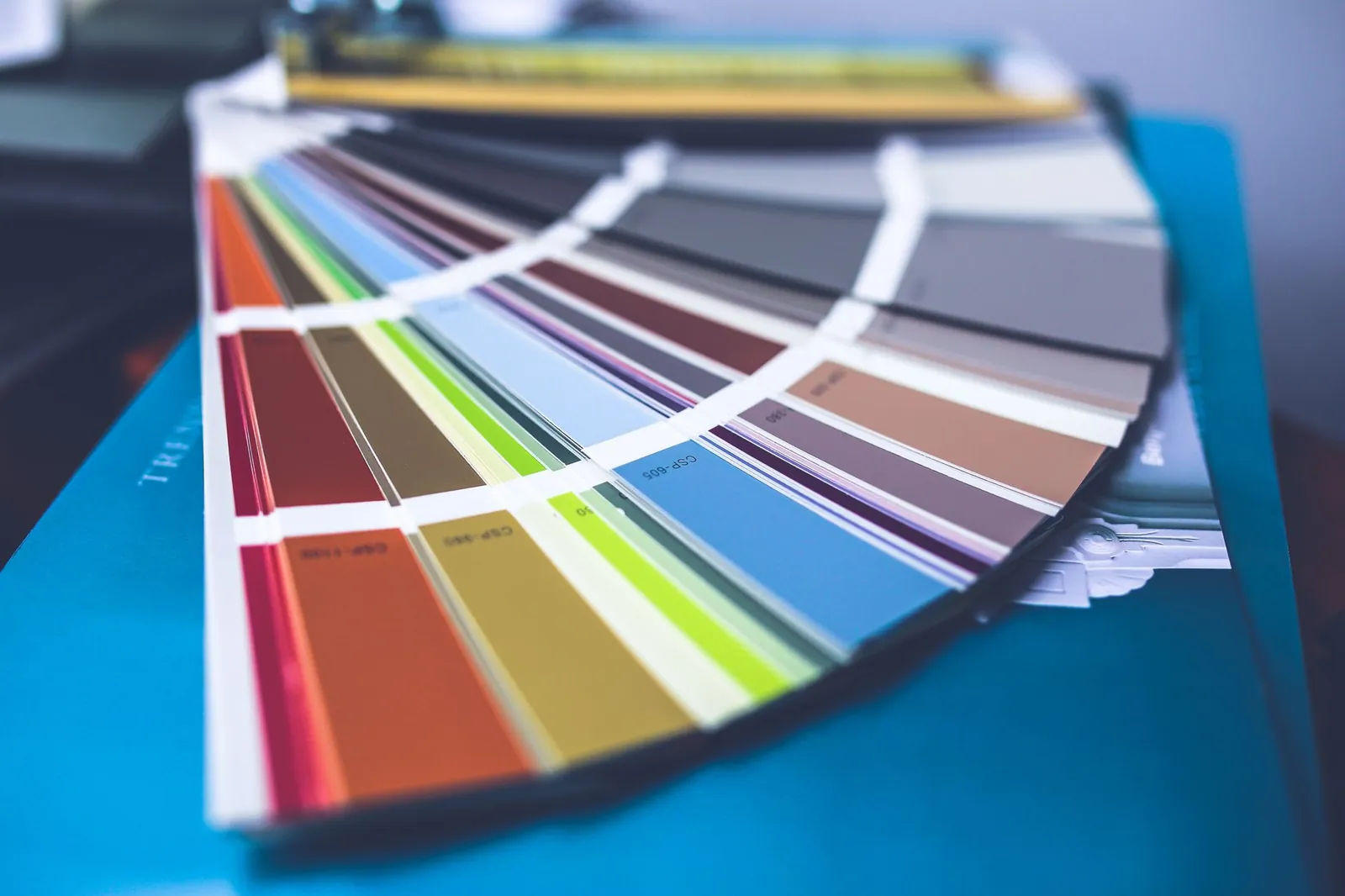 Paint sample squares in three shades taped beside warm wood cabinetry and a stone countertop to check undertone compatibility