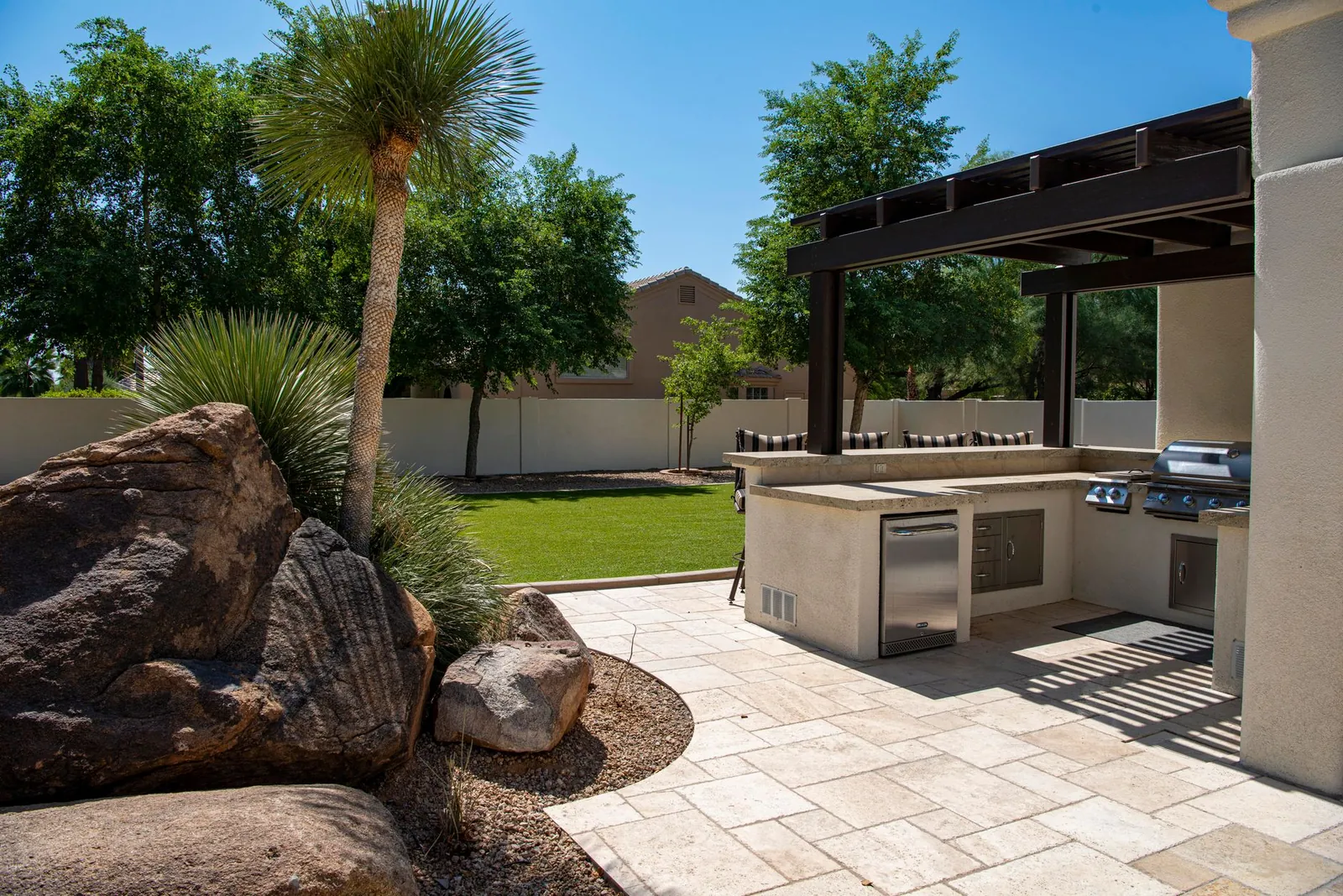 Overhead view of a finished herringbone-pattern patio in light gray porcelain pavers, with tight joints and a clean border course