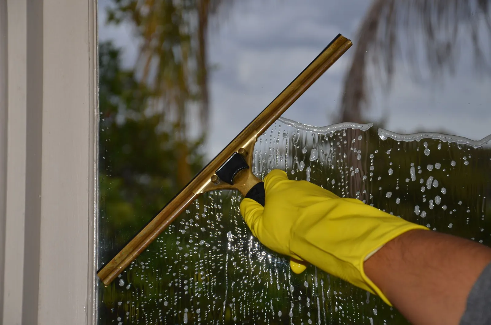 Squeegee and microfiber cloth laid on a windowsill beside a spray bottle of vinegar solution