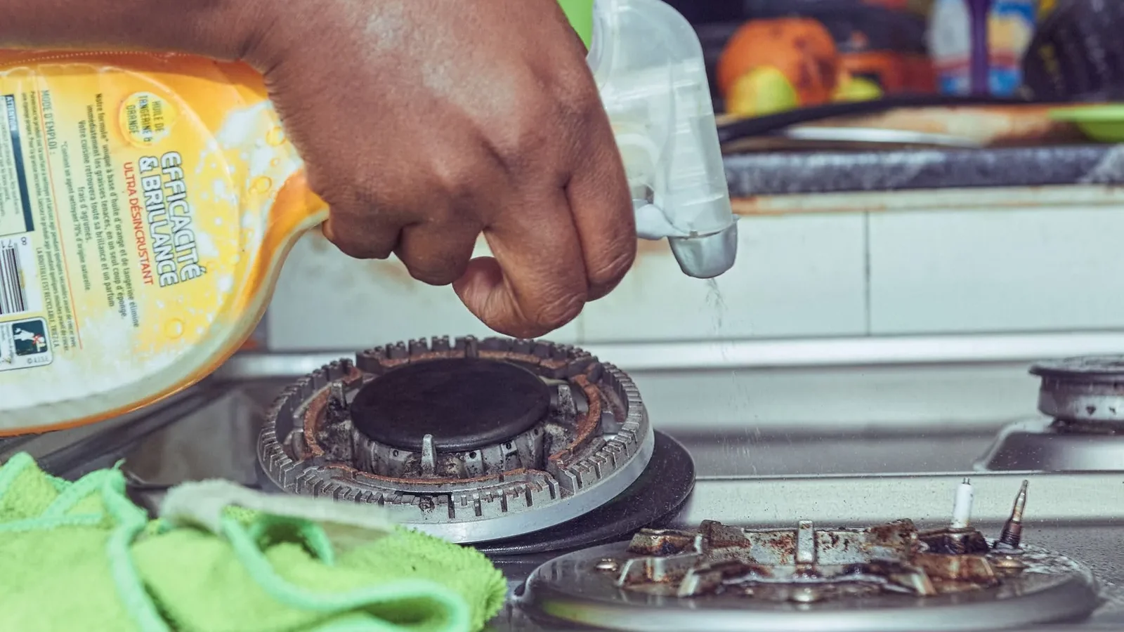 Microfibre cloths, spray bottles, rubber gloves, and a scrub brush arranged on a kitchen counter before a deep clean