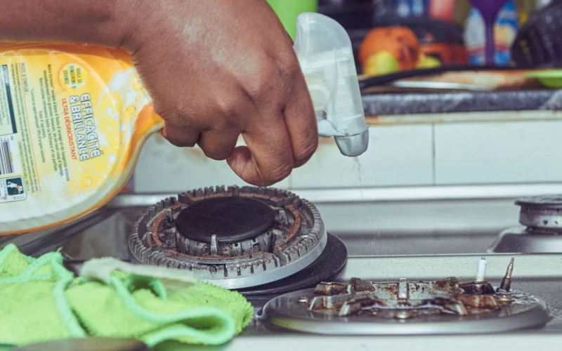 Microfibre cloths, spray bottles, rubber gloves, and a scrub brush arranged on a kitchen counter before a deep clean