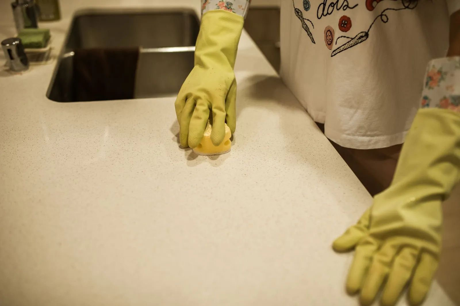 Wiping the interior shelf of a kitchen cabinet with a damp cloth after removing all stored items