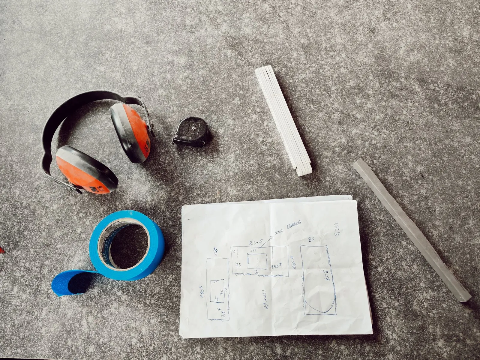 Tape measure laid across a patio with hand-drawn graph paper sketch showing dimensions, fixed features, and sun exposure notes