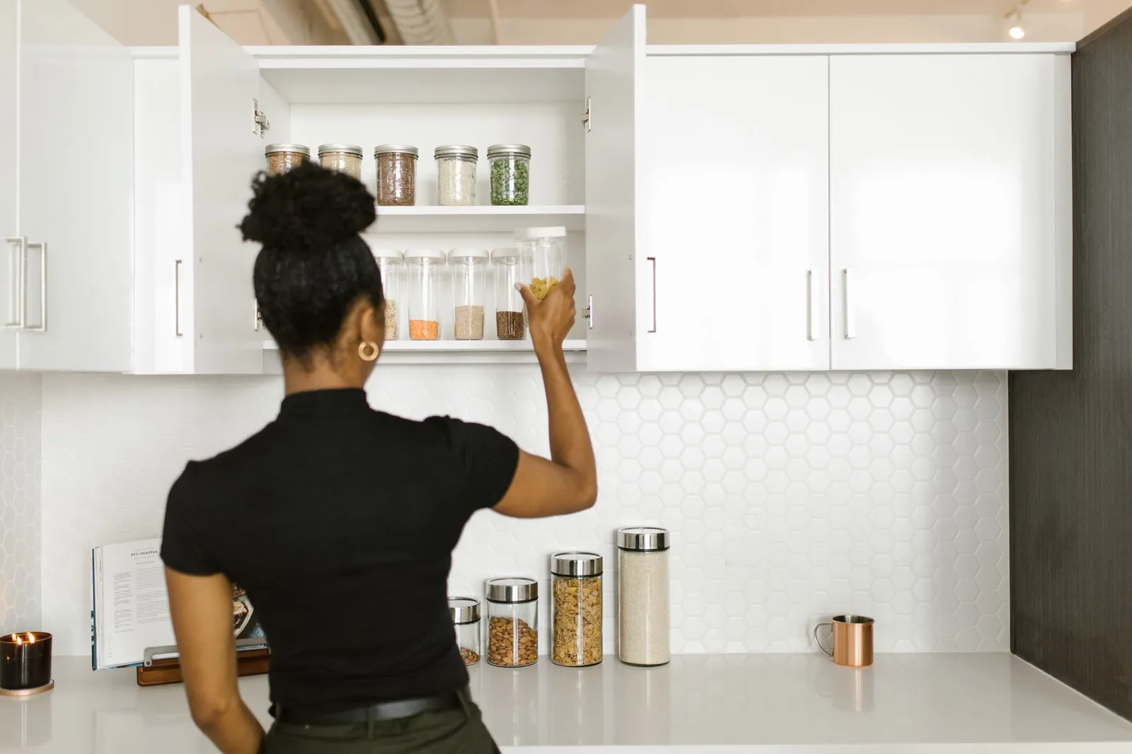 Labeled airtight containers and glass jars stacked on pantry shelves beside a lazy Susan turntable holding oils and vinegars