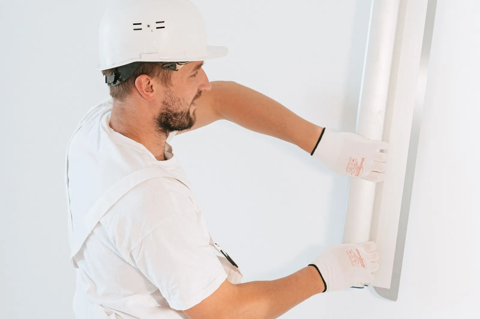 Putty knife and joint compound beside a small nail hole in a painted drywall wall, ready for repair