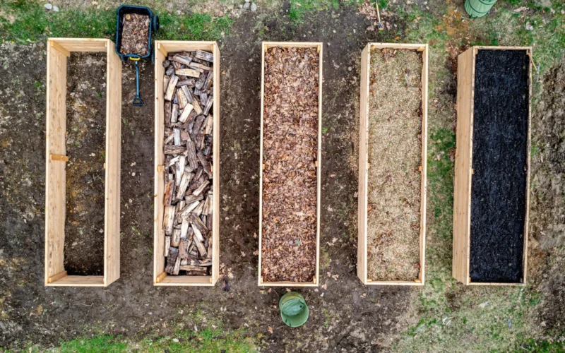 Three piles of ingredients for raised bed soil mix: topsoil, finished compost, and peat moss arranged in 40-30-30 proportions