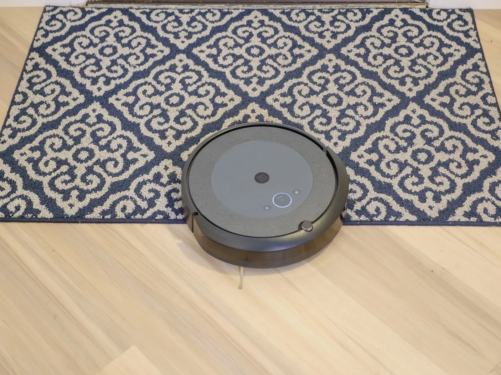 Hand emptying a robot vacuum dustbin next to a full upright vacuum tank, showing capacity difference
