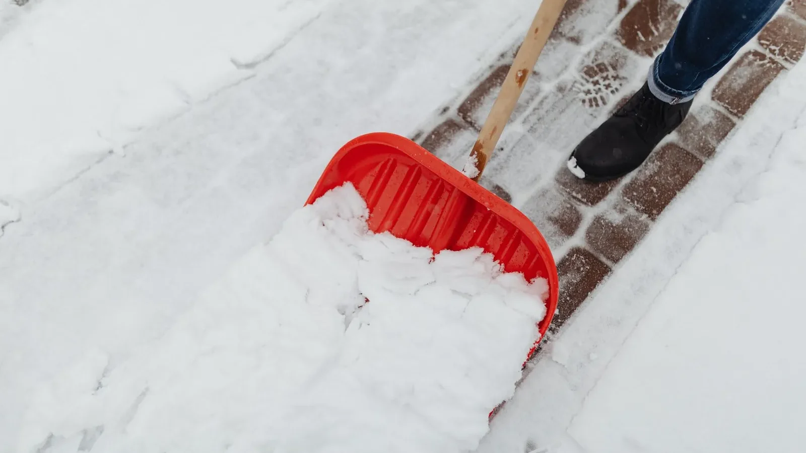 Homeowner clearing leaves and shingle granules from a residential gutter in early spring