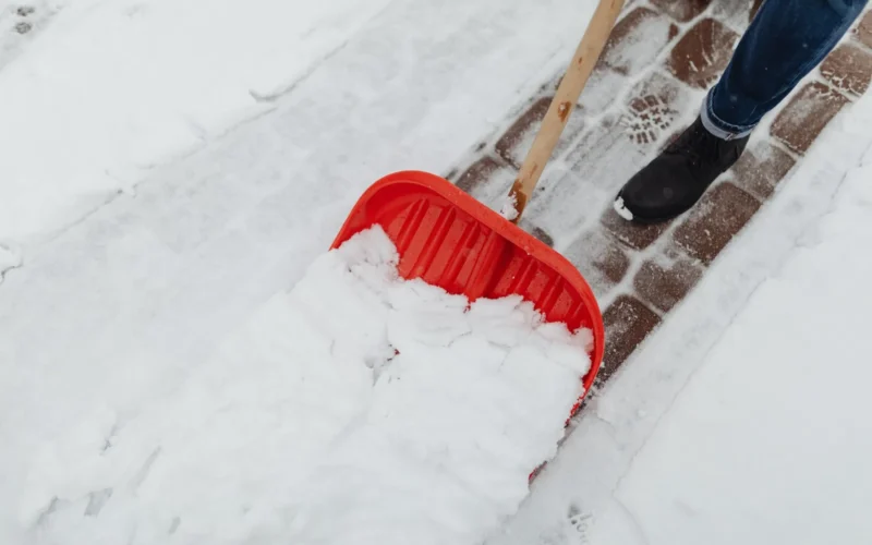 Homeowner clearing leaves and shingle granules from a residential gutter in early spring